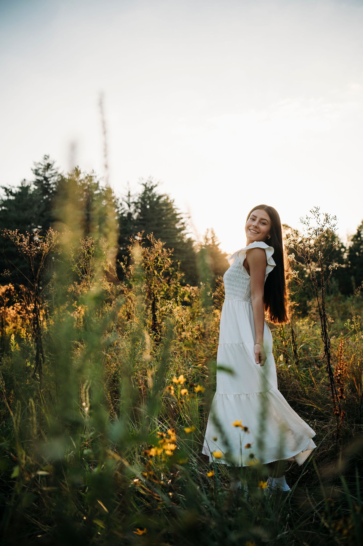 Emily in a white dress surrounded by tall grass during her golden hour senior portraits at Otter Creek Park Brandenburg KY.