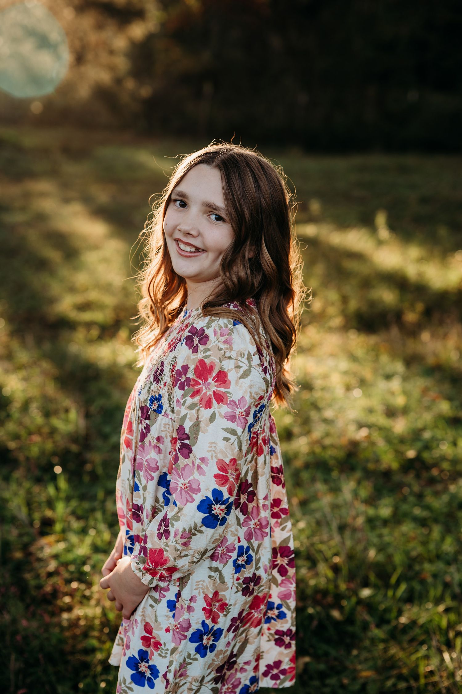 Girl in floral dress smiling in golden sunlight during fall photo session in Guston Kentucky