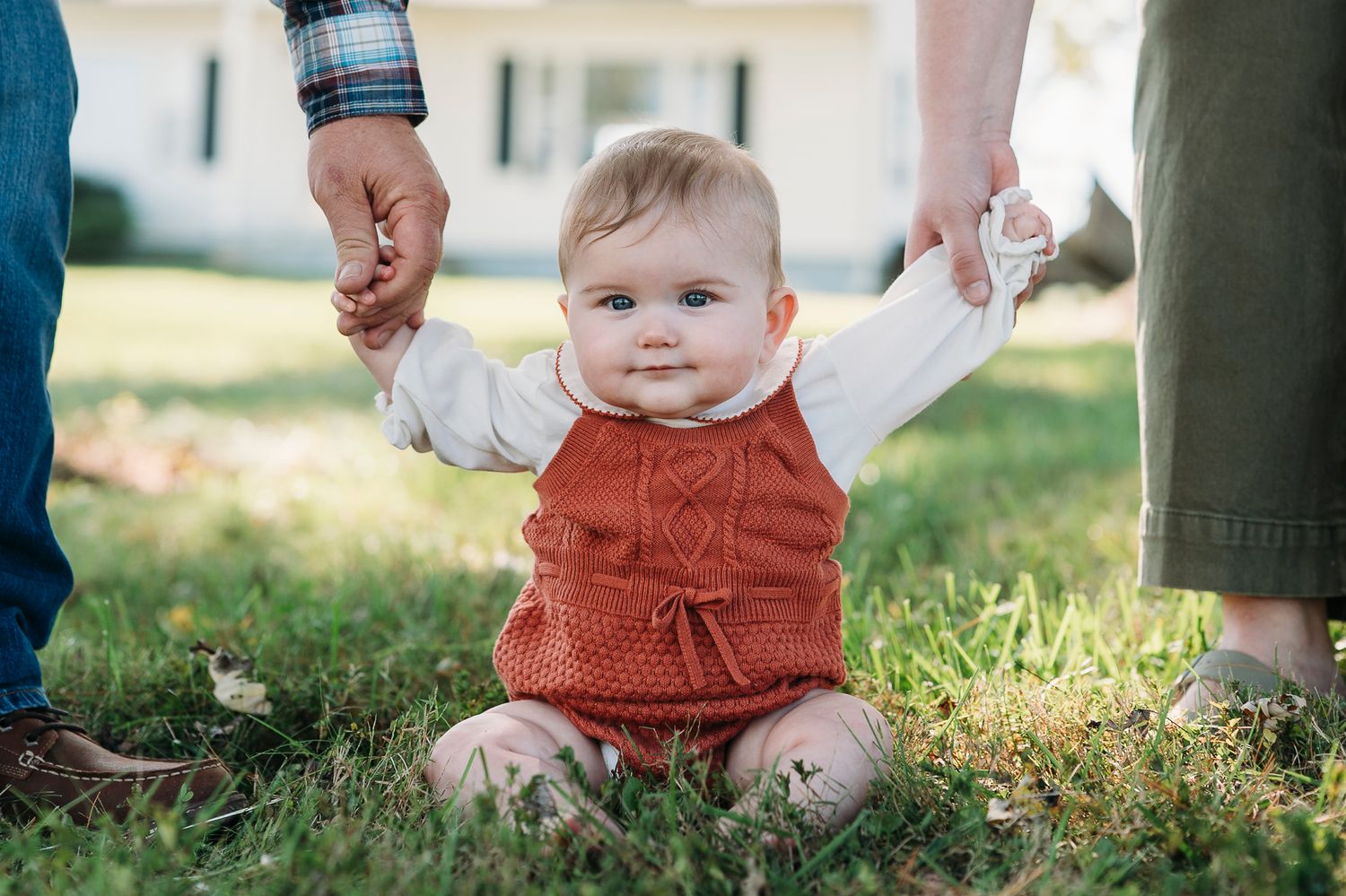 Baby holding parents’ hands during a farmhouse family photo session in Battletown Kentucky captured by ninefifteenphoto