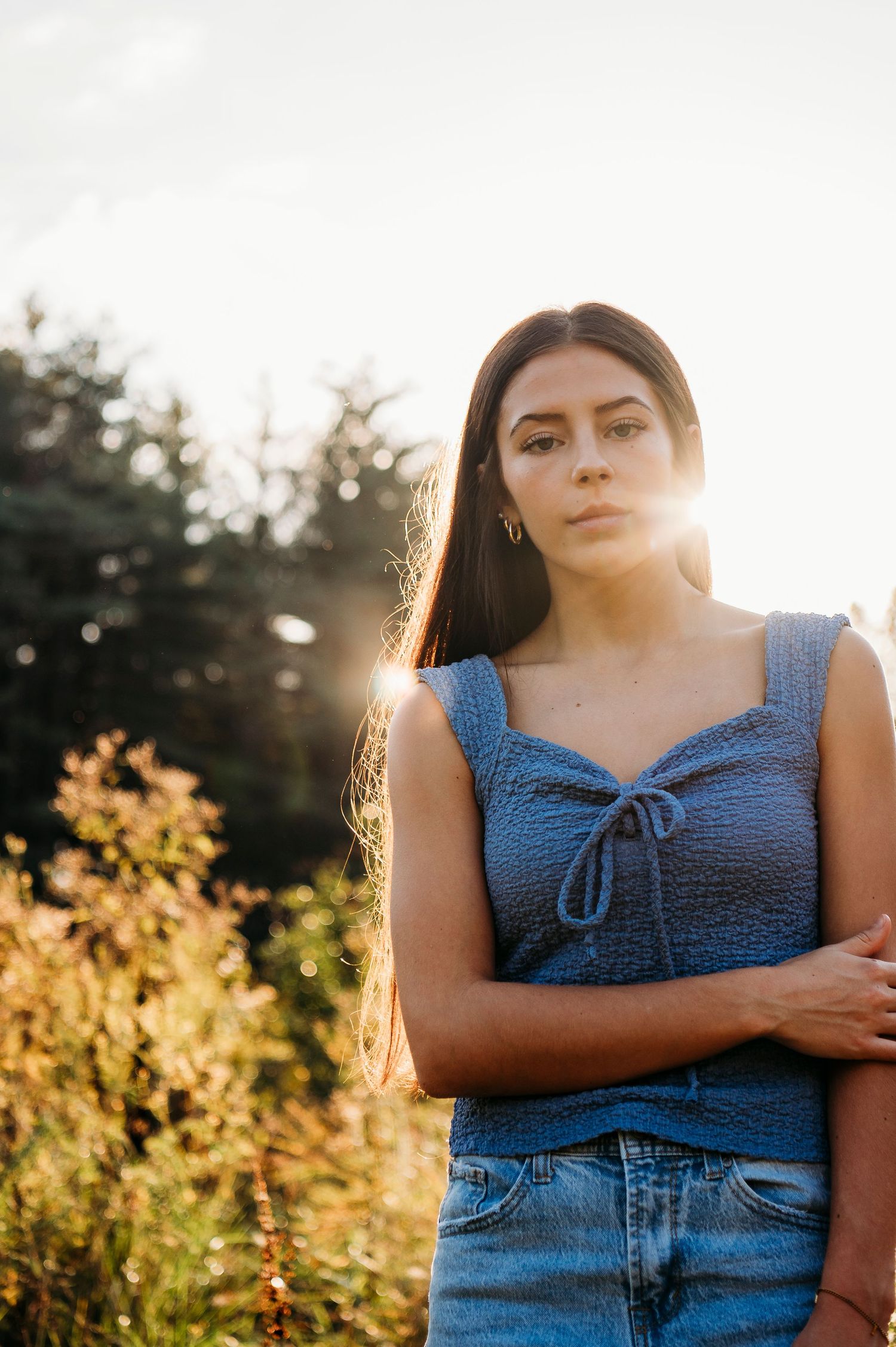 Close-up portrait of Emily in a blue top surrounded by warm fall light during her Brandenburg KY senior photos.