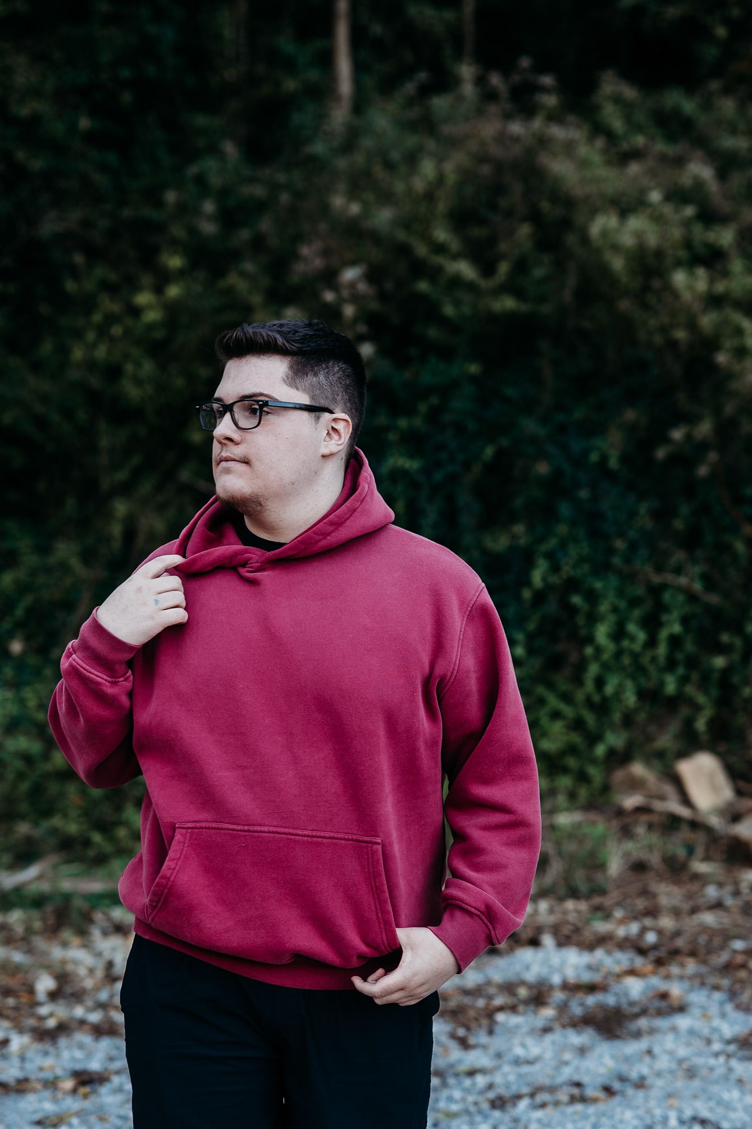 Luca wearing a red hoodie, hands in pocket, looking off camera during his senior session in Brandenburg KY.