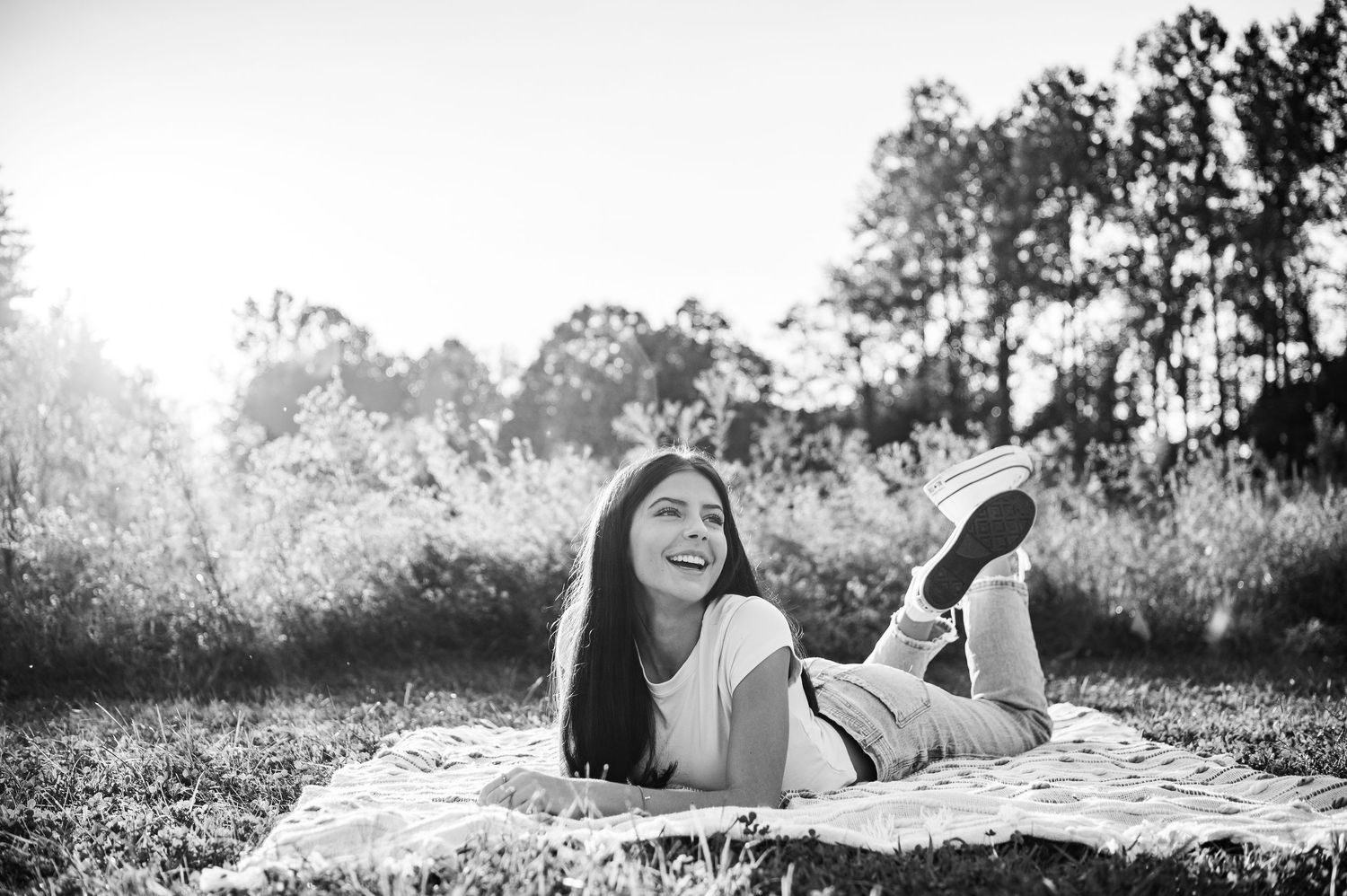 Black and white senior portrait of Emily sitting in a wildflower field at Otter Creek Park in Brandenburg Kentucky.