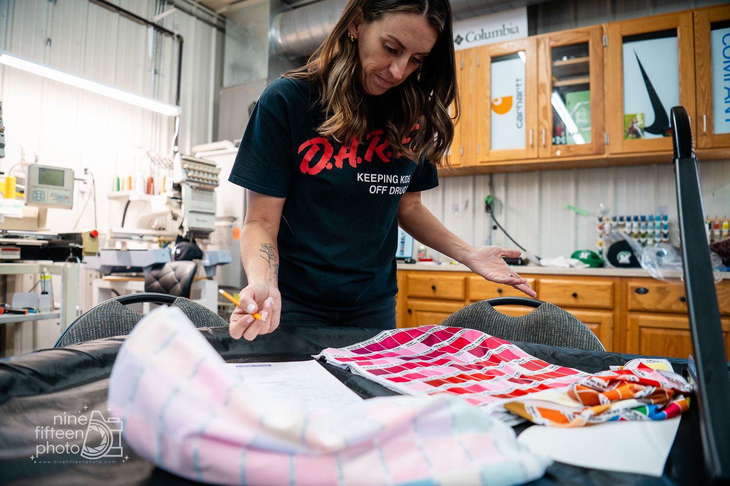 Woman ironing colorful apparel inside MC Screen Printing custom apparel shop in Brandenburg Kentucky.