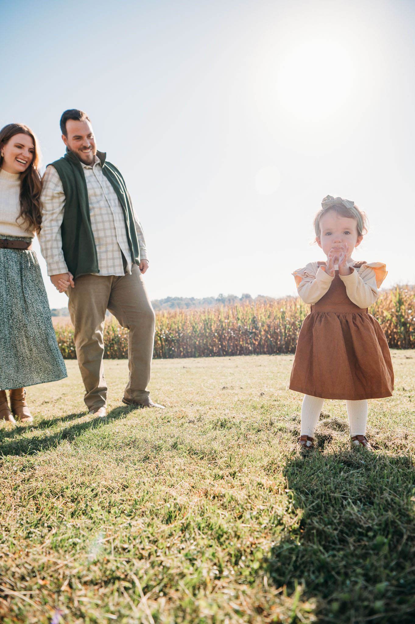 Family walking through golden field with toddler during outdoor fall photo session in Brandenburg Kentucky.