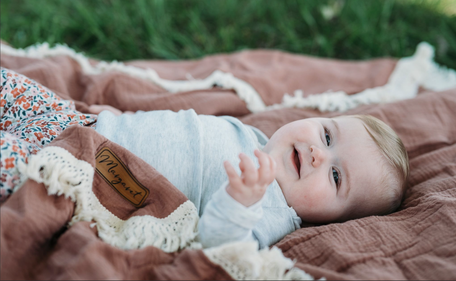 Baby lying on soft blanket outdoors during family photo session in Meade County KY.