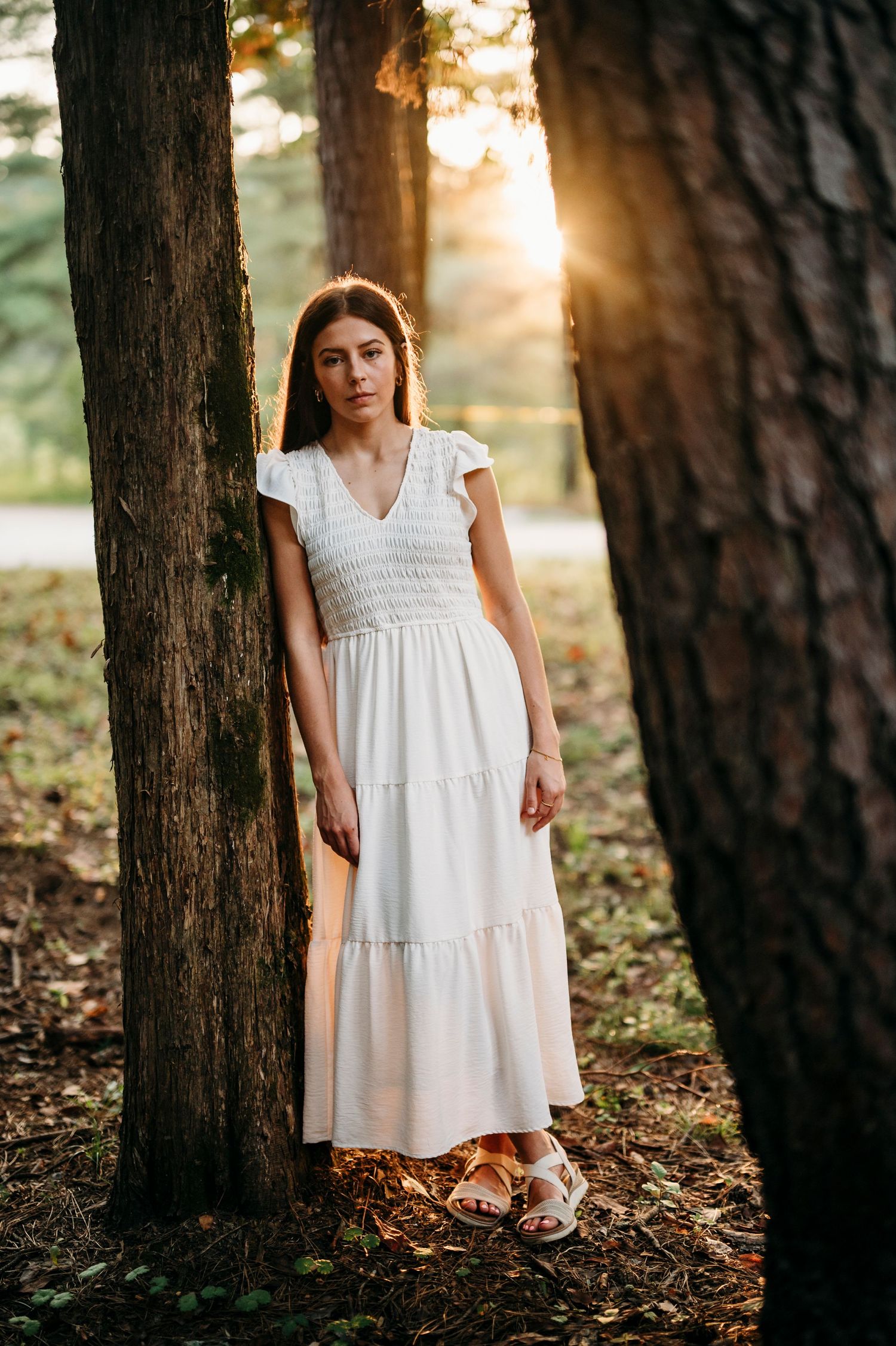 Emily standing beside trees in her white dress during her senior photo session at Otter Creek Park Brandenburg KY.