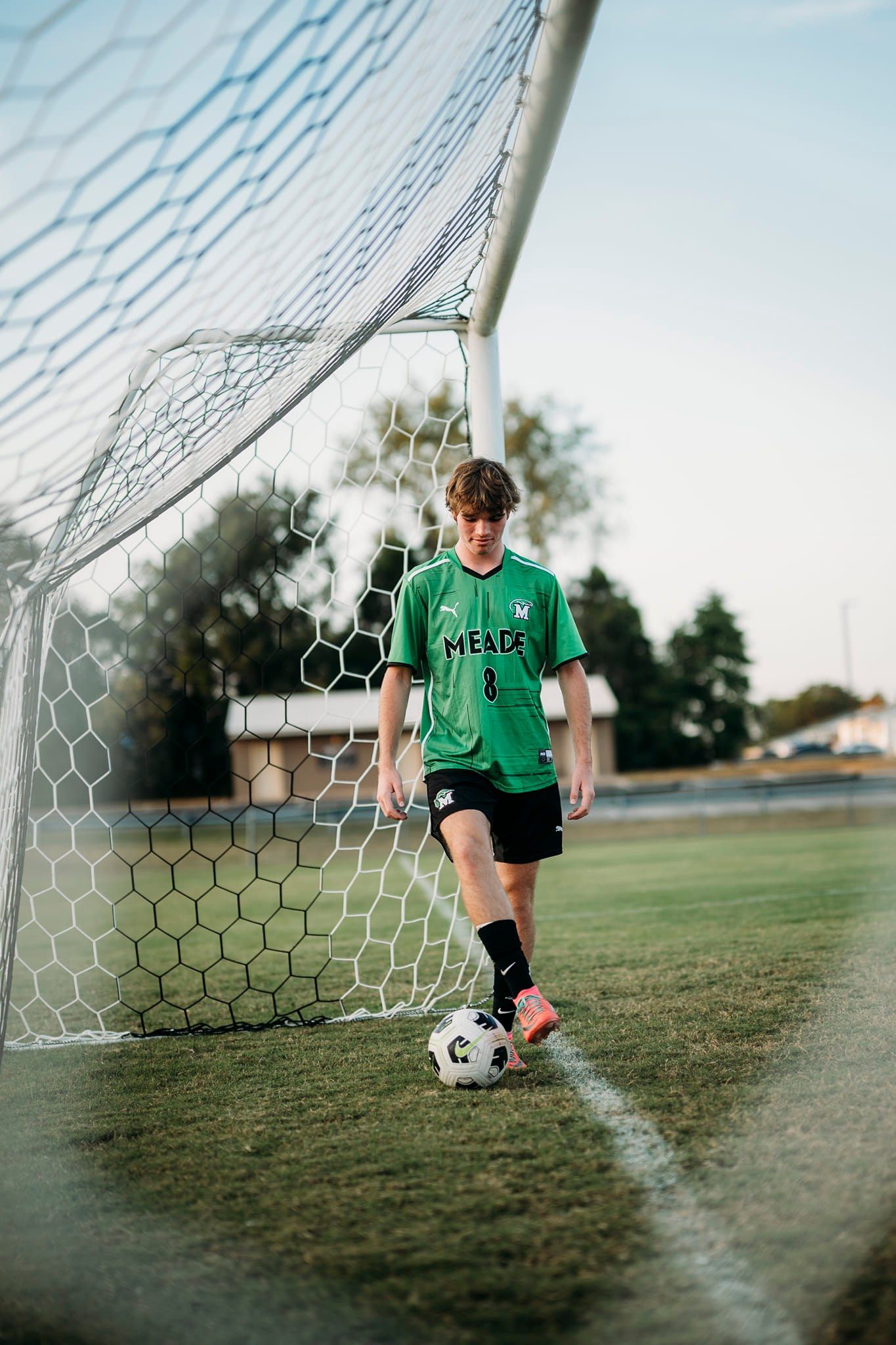 Senior soccer player running across the field in uniform during sunset action portrait.