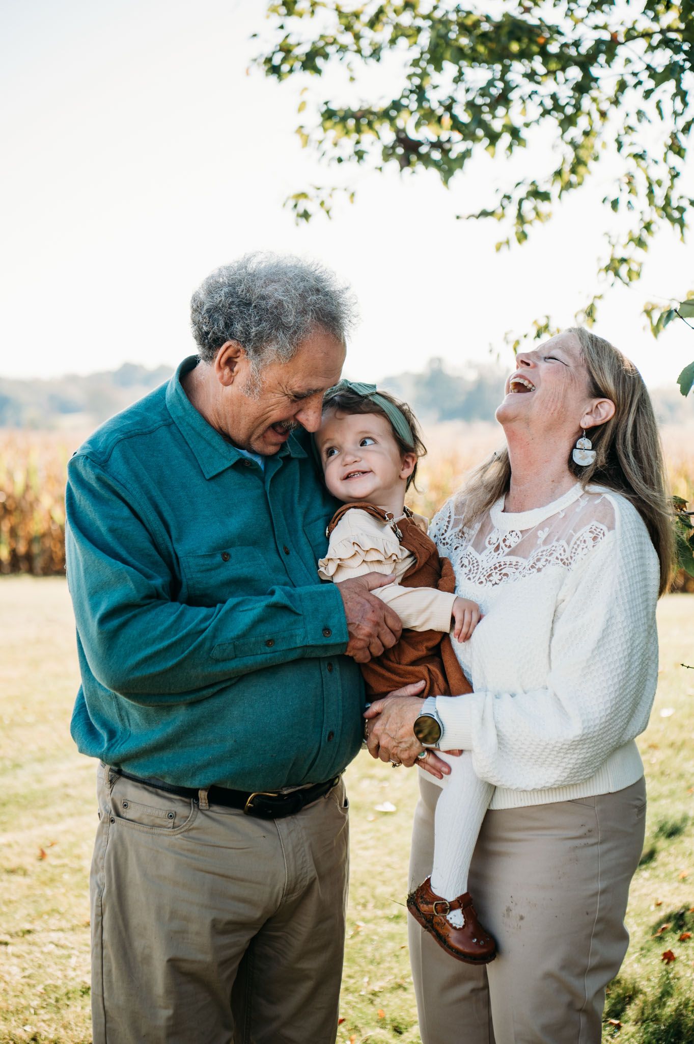 Grandparents sharing laughter with grandchild outdoors on a sunny Meade County fall day.