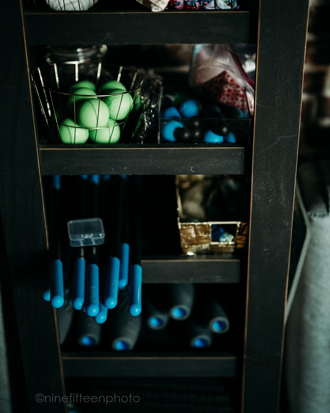Dark wooden shelf displays green spheres, blue taper candles, and mystical shop supplies.
