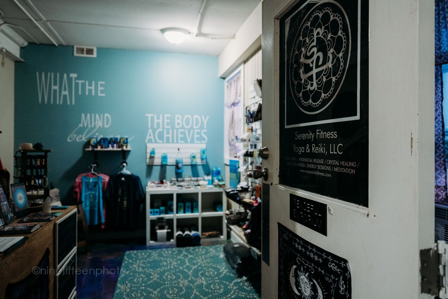 Wellness studio interior with teal wall quote about mind and body, retail shelves, and merchandise.