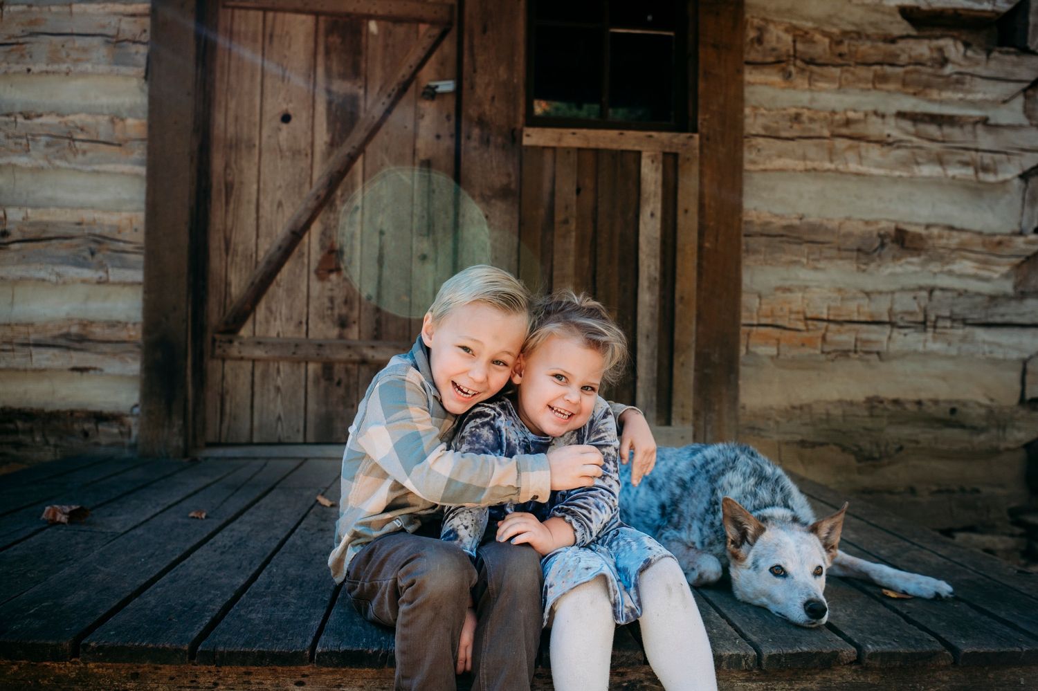 Two children play and cuddle and hang with their dog during a photo session with ninefifteenphoto.