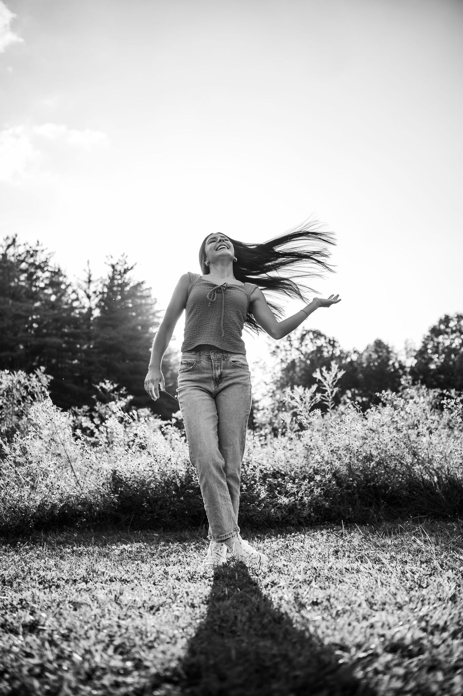 Black and white photo of Emily twirling in a field during her senior session at Otter Creek Park in Brandenburg KY.