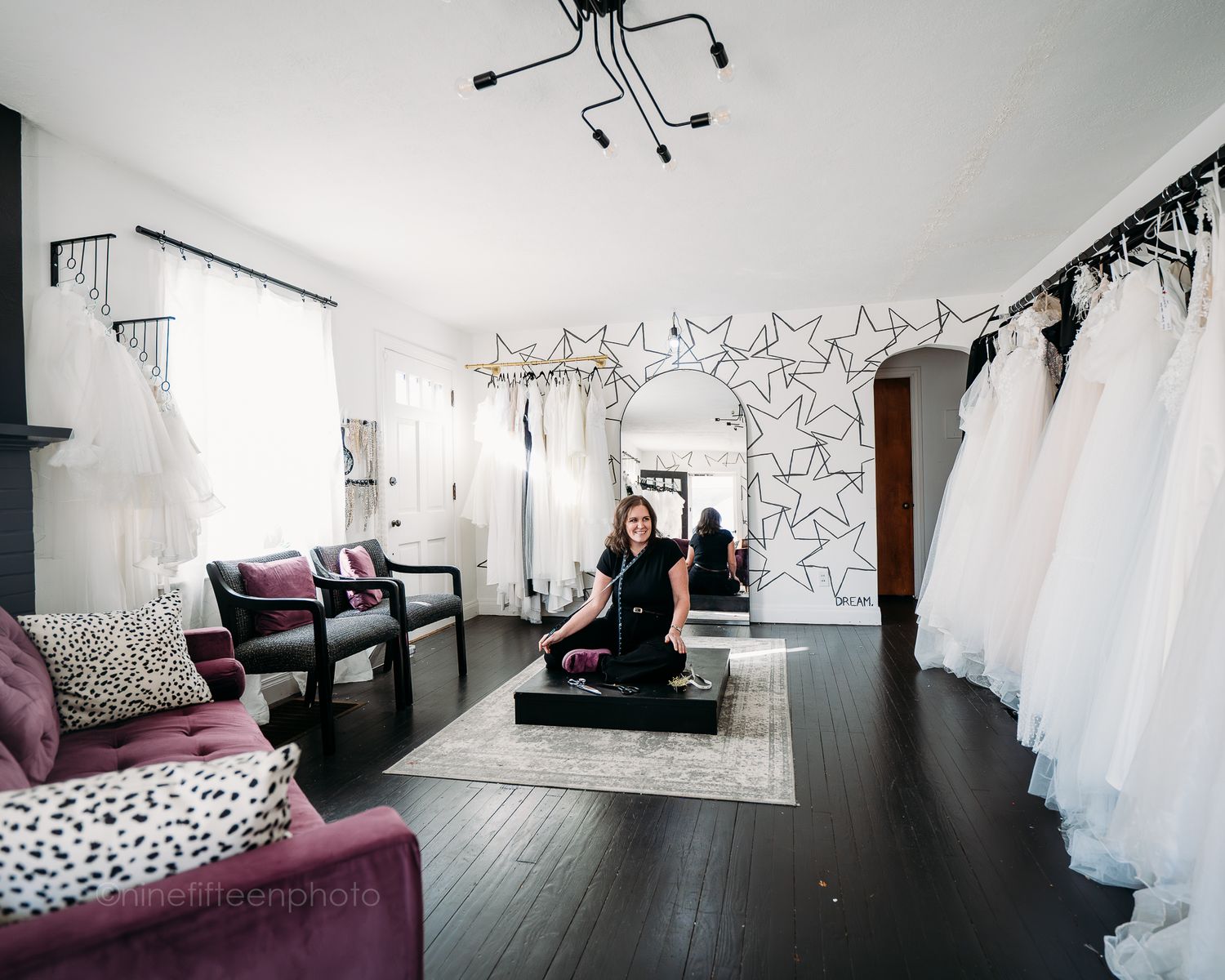 Bridal boutique interior with white wedding gowns on racks and star wall decor.