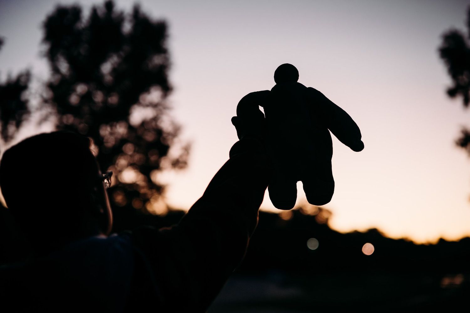 Luca holding a Baymax figure in silhouette at sunset during his creative senior photo session in Brandenburg KY.