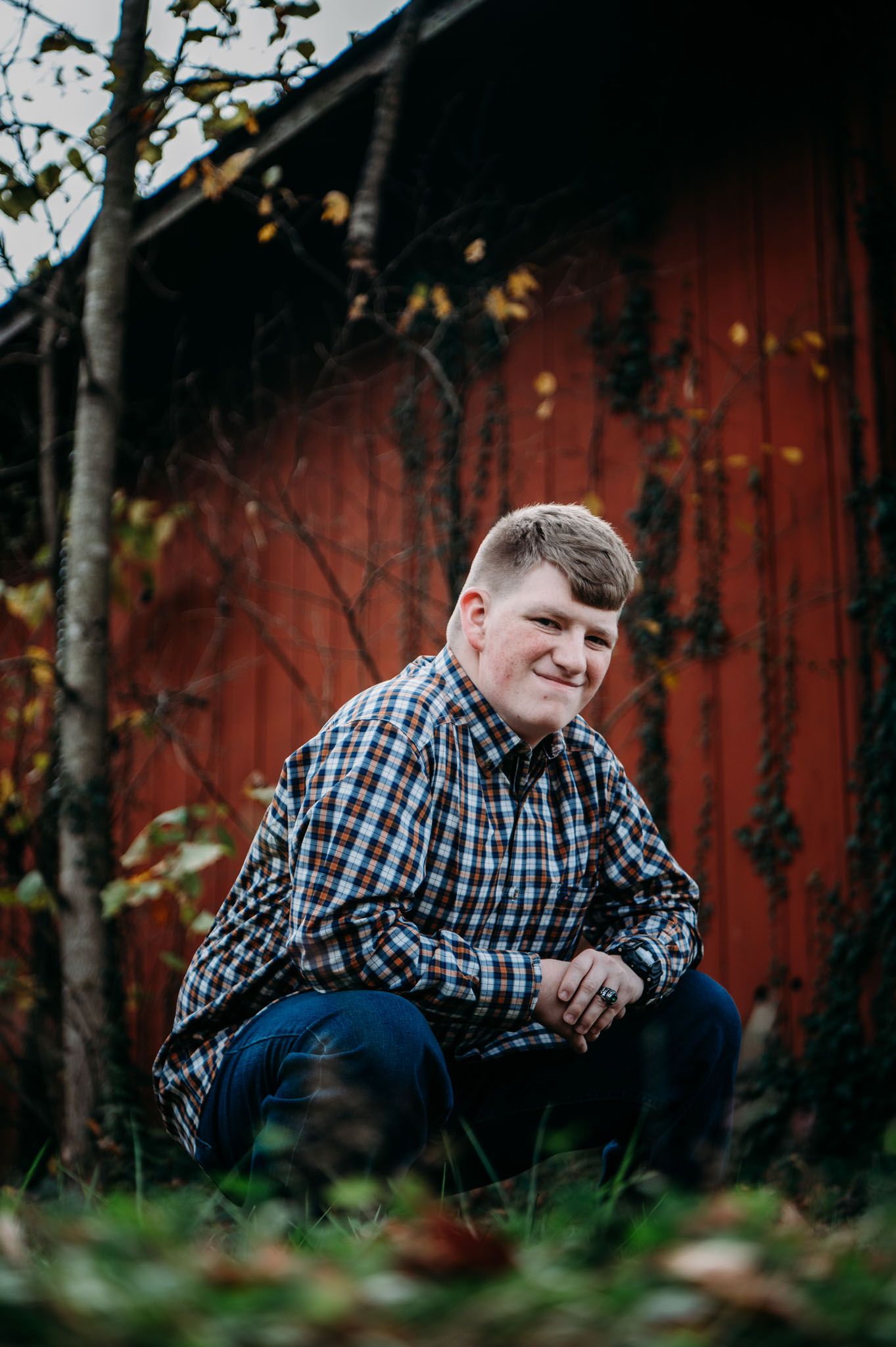 Mayson leans by a rustic red barn during his FFA senior photo session in Meade County KY