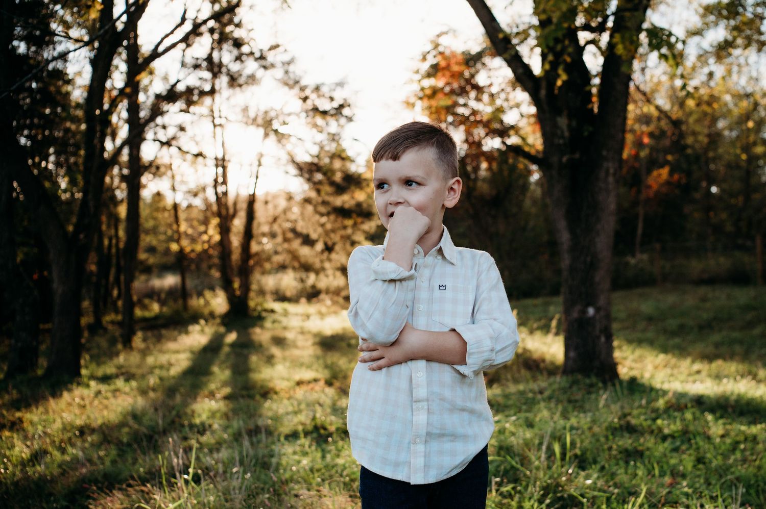 Boy standing in wooded field with golden fall light during Guston Kentucky family session