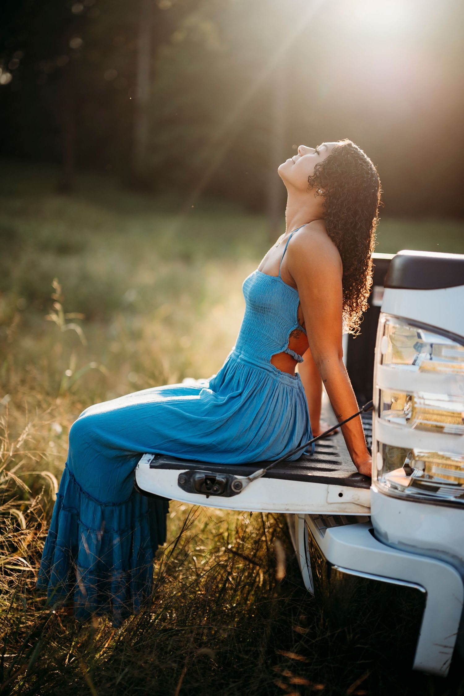 Bella sitting on truck tailgate at sunset in Brandenburg KY during senior photo session by ninefifteenphoto