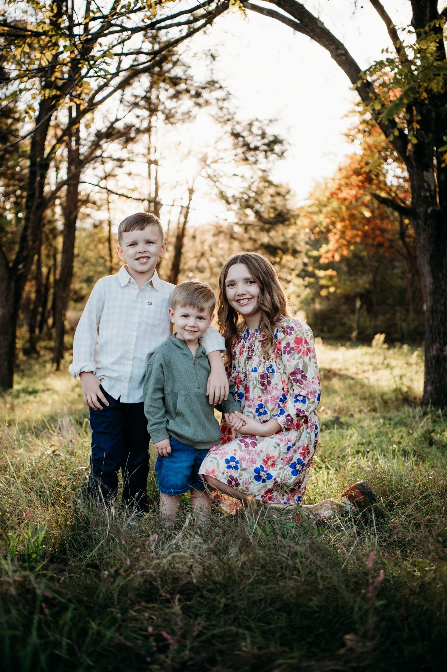 Brother and sister kneeling together in glowing field at sunset in Guston Kentucky