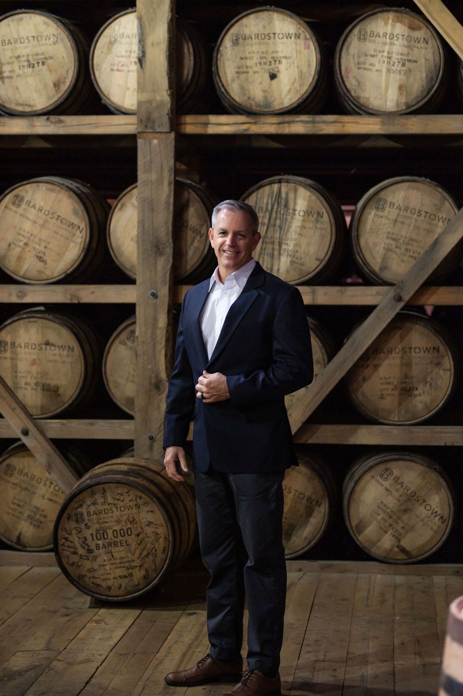 Professional portrait of man in suit with bourbon barrels, ninefifteenphoto Brandenburg KY branding photographer in Meade County.