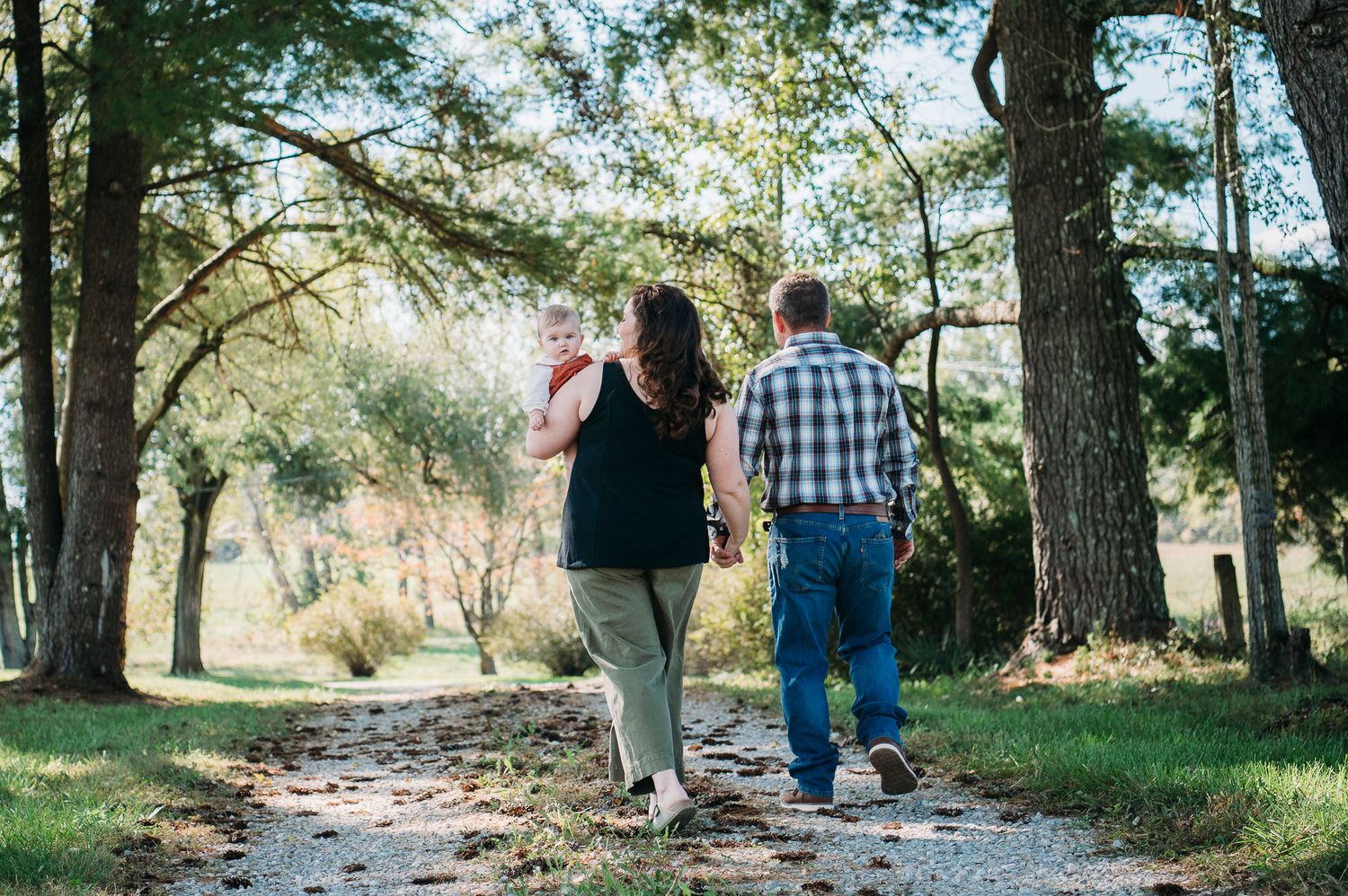 Family walking down a tree-lined driveway during a Battletown KY farmhouse photo session by ninefifteenphoto.