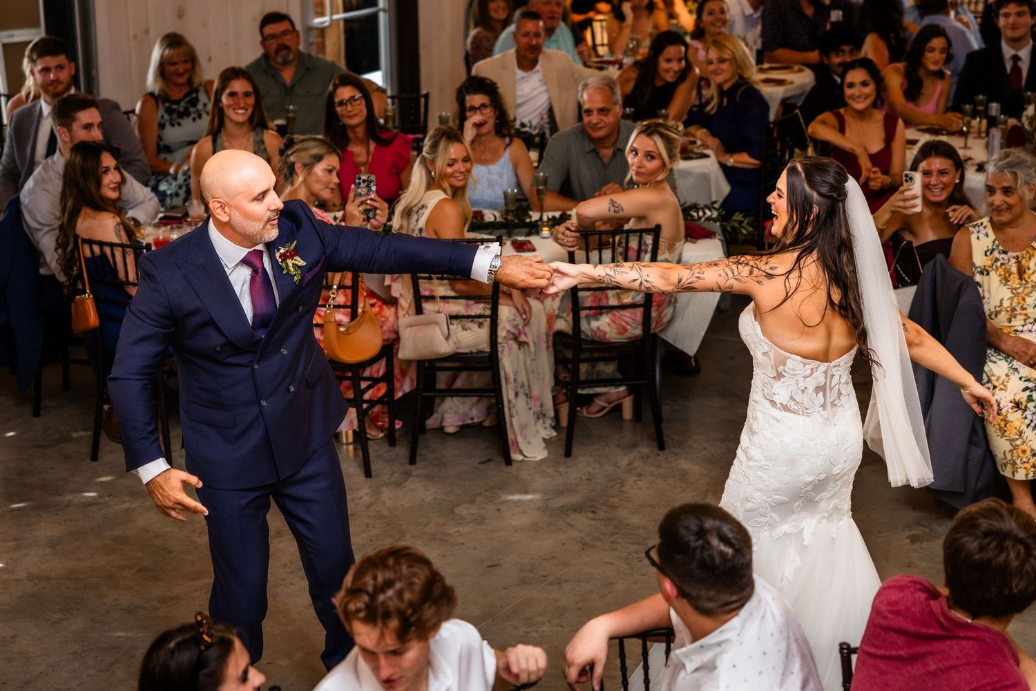 Bride and groom share first dance at wedding reception while guests watch and celebrate in elegant venue.