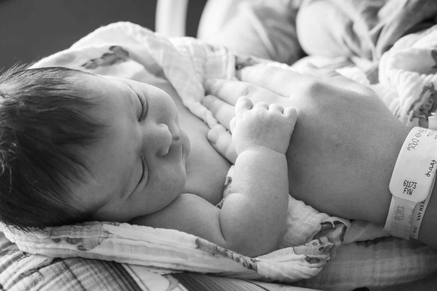 Peaceful sleeping newborn baby wrapped in a soft blanket in black and white photography.