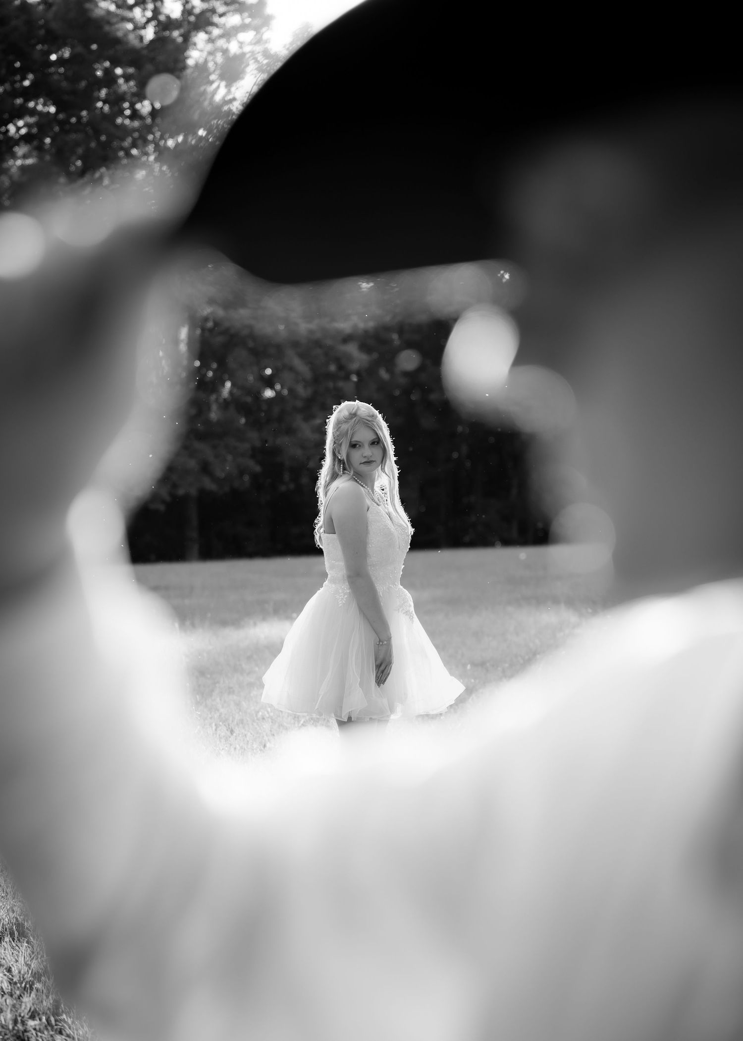 Creative black and white photo of bride reflected in grooms hat mirror outdoors.