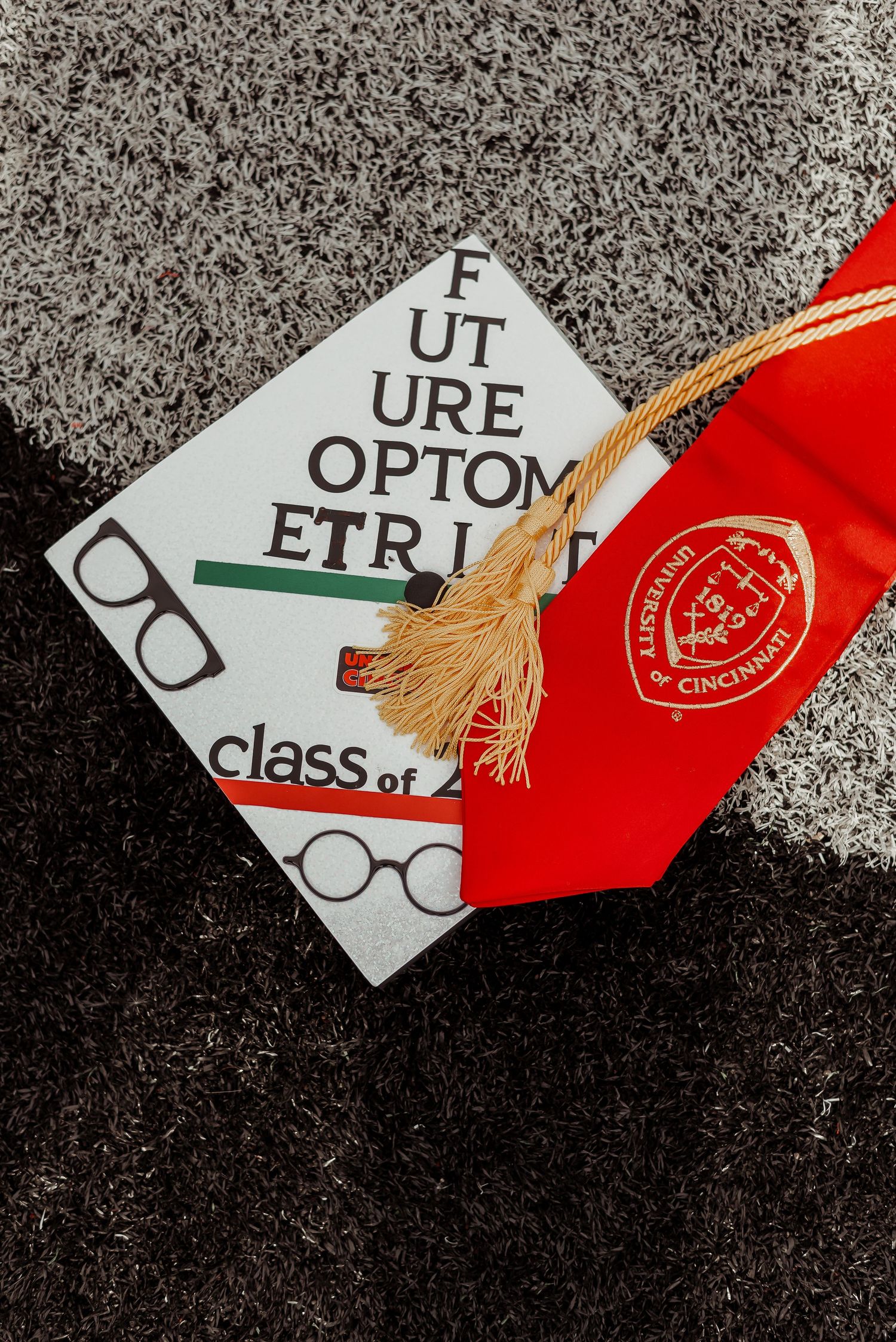 University of Cincinnati Future Optometrist graduation cap decorated with glasses and green stripe, Class of 2024.