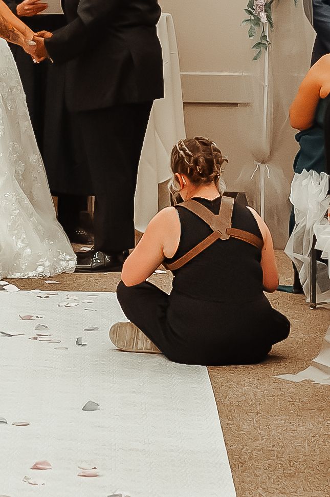 Photographer sitting on floor at wedding ceremony capturing couple from ground level.