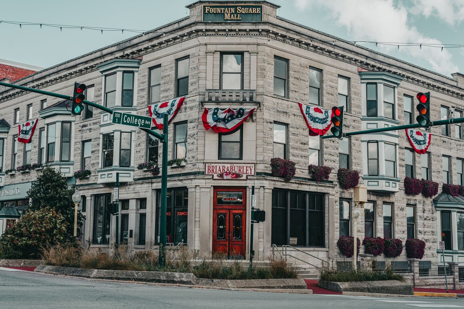 Historic stone corner building decorated with patriotic bunting and flags at a small town intersection.