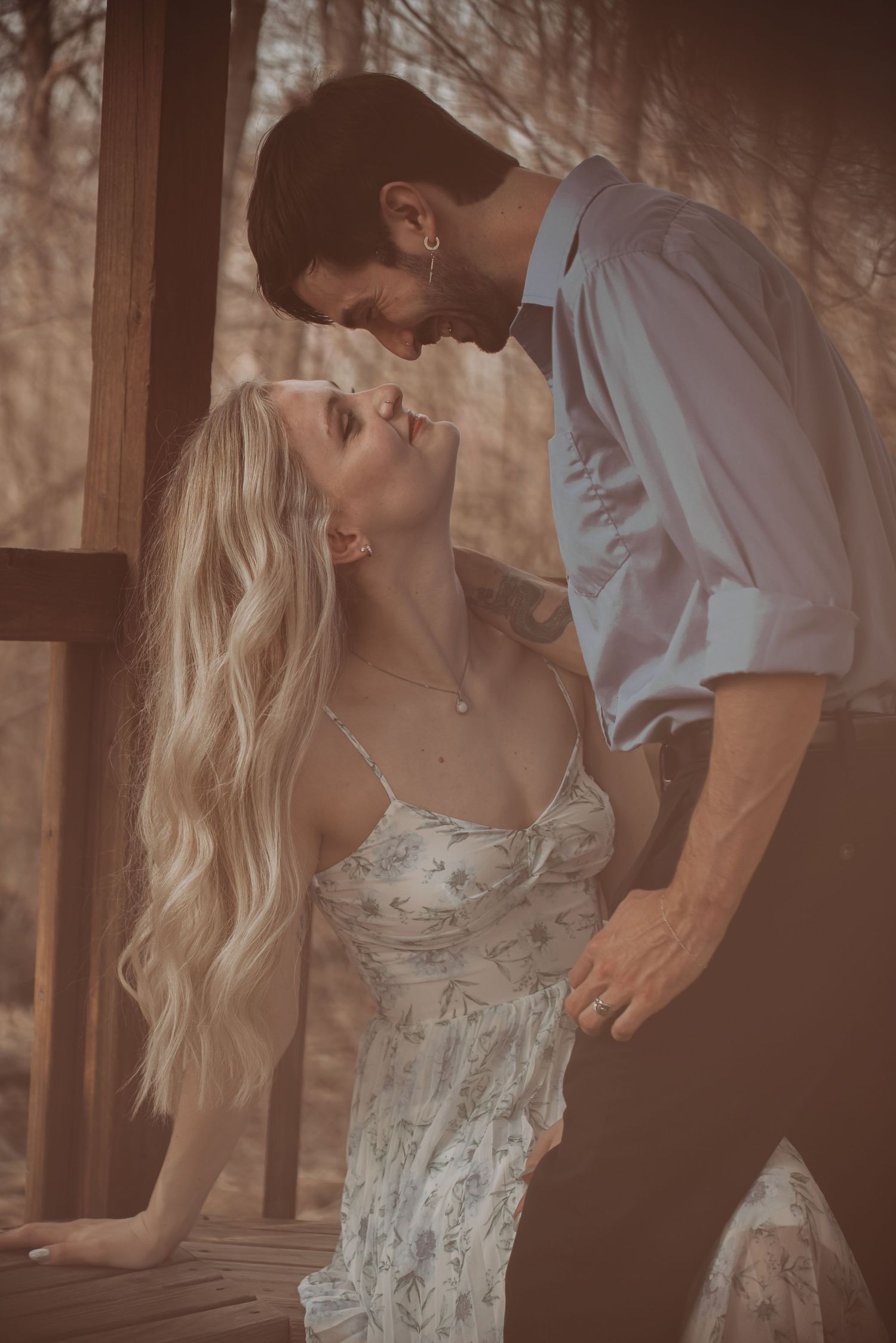 Romantic couple nearly kissing in warm vintage-toned light on a wooden porch in the woods.
