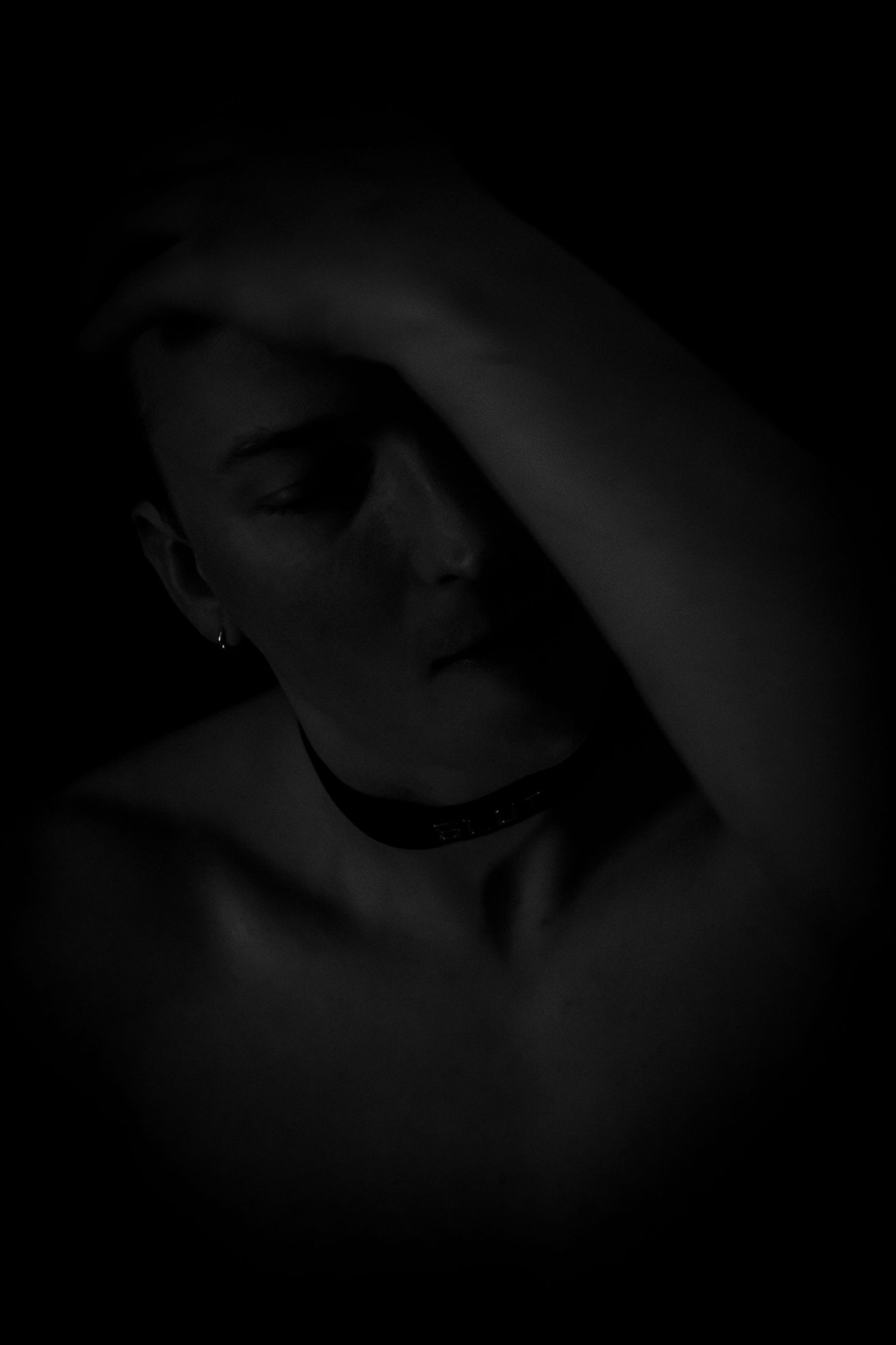 Moody black and white portrait showing a shadowy silhouette against dark background.