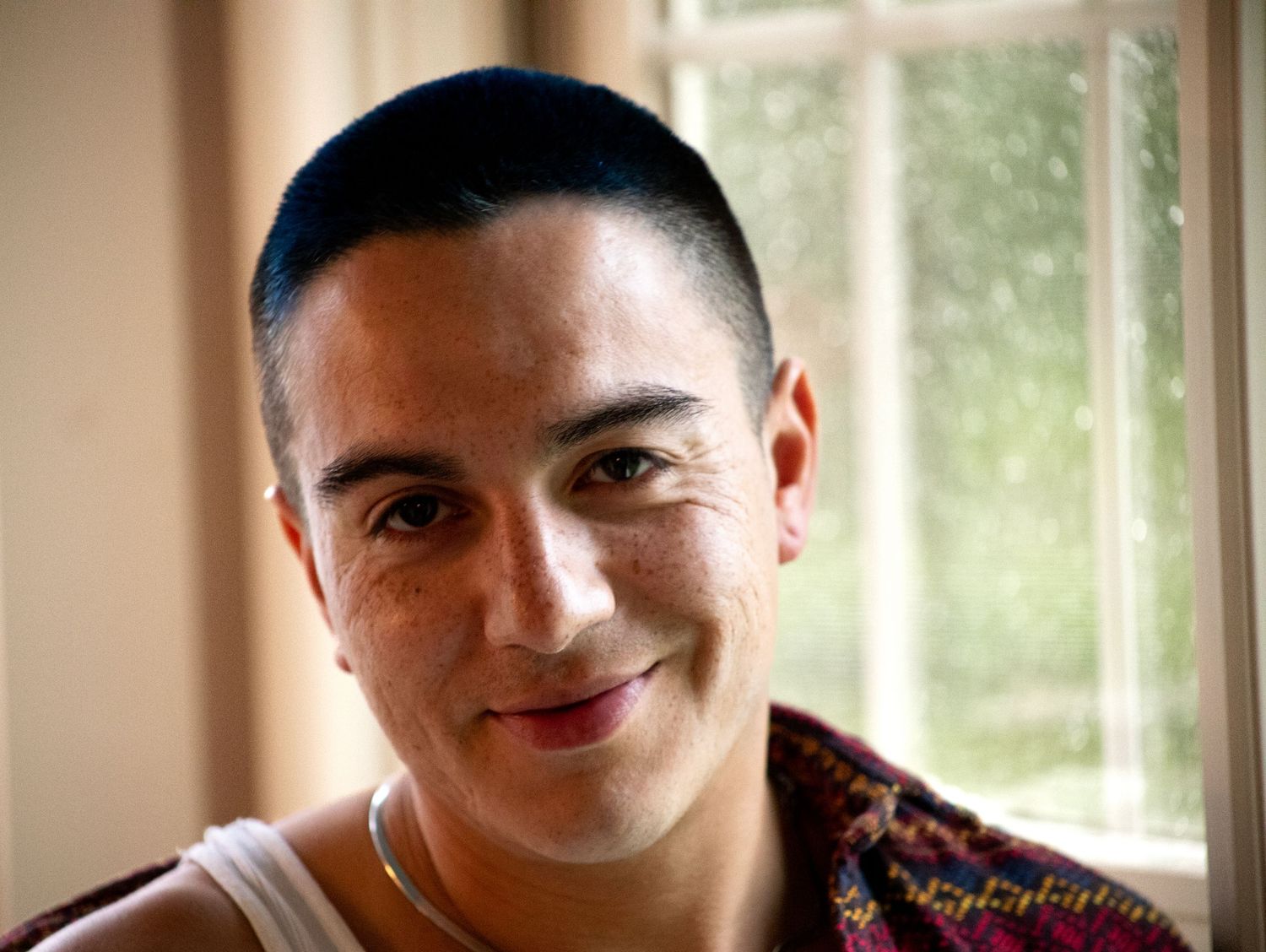 Warm-toned portrait showing a genuine smile in natural window light.