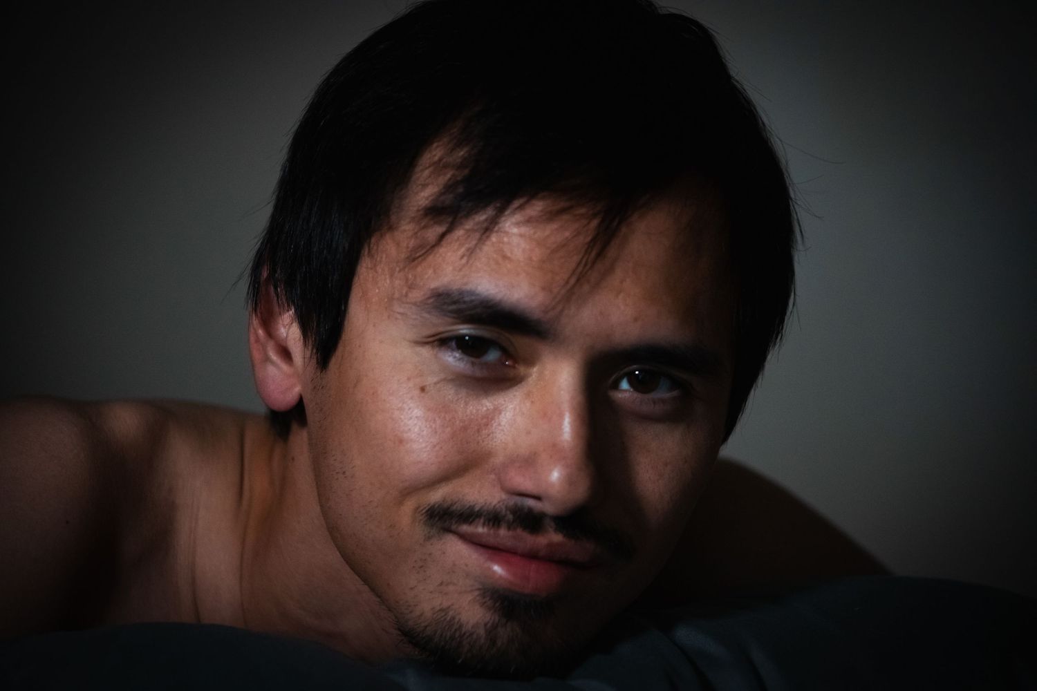 Dramatic low-key portrait of a person against dark background.