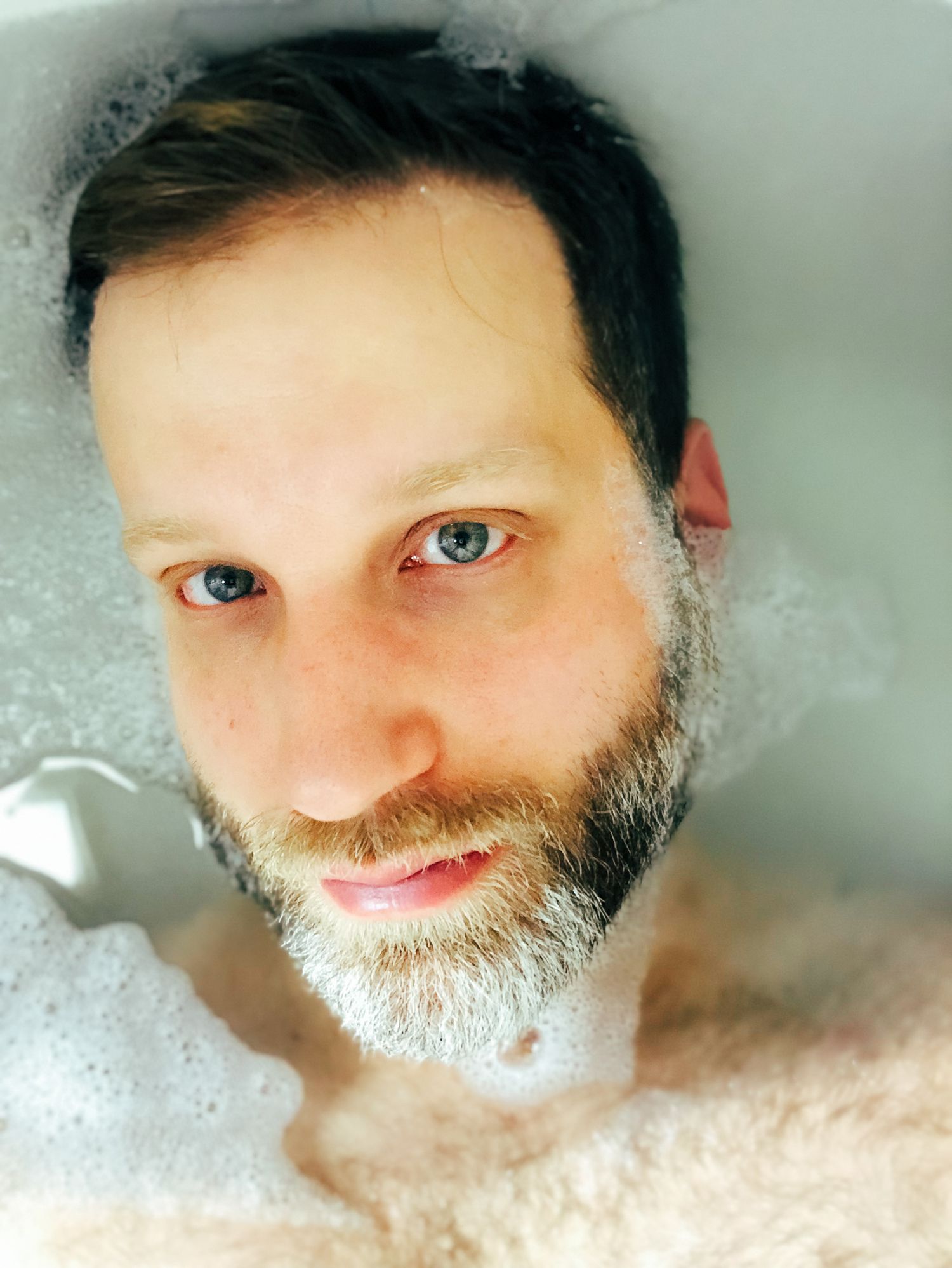 Close-up portrait surrounded by bubbles or foam in bright lighting.