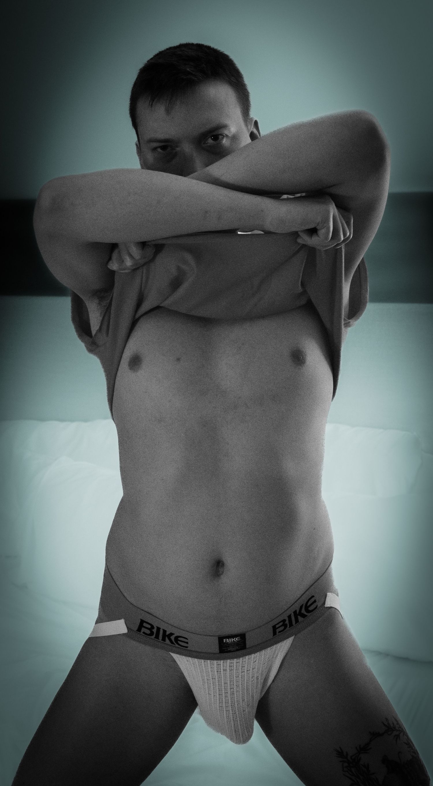 Monochromatic body study with dramatic lighting and shadows.