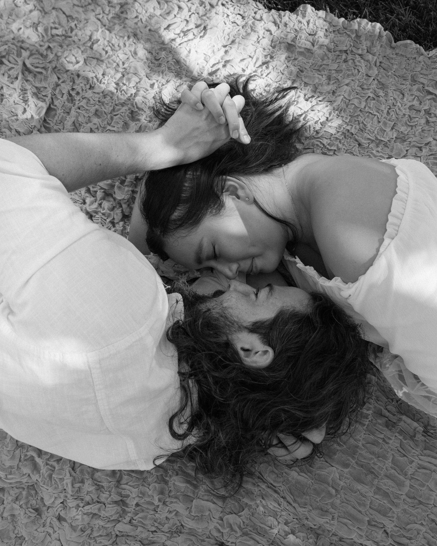 Black and white artistic photos showing two people in intimate poses on a textured surface.