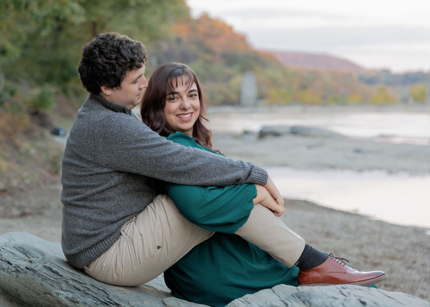 Couple sitting together on a fallen log at the beach during sunset enjoying a romantic moment.