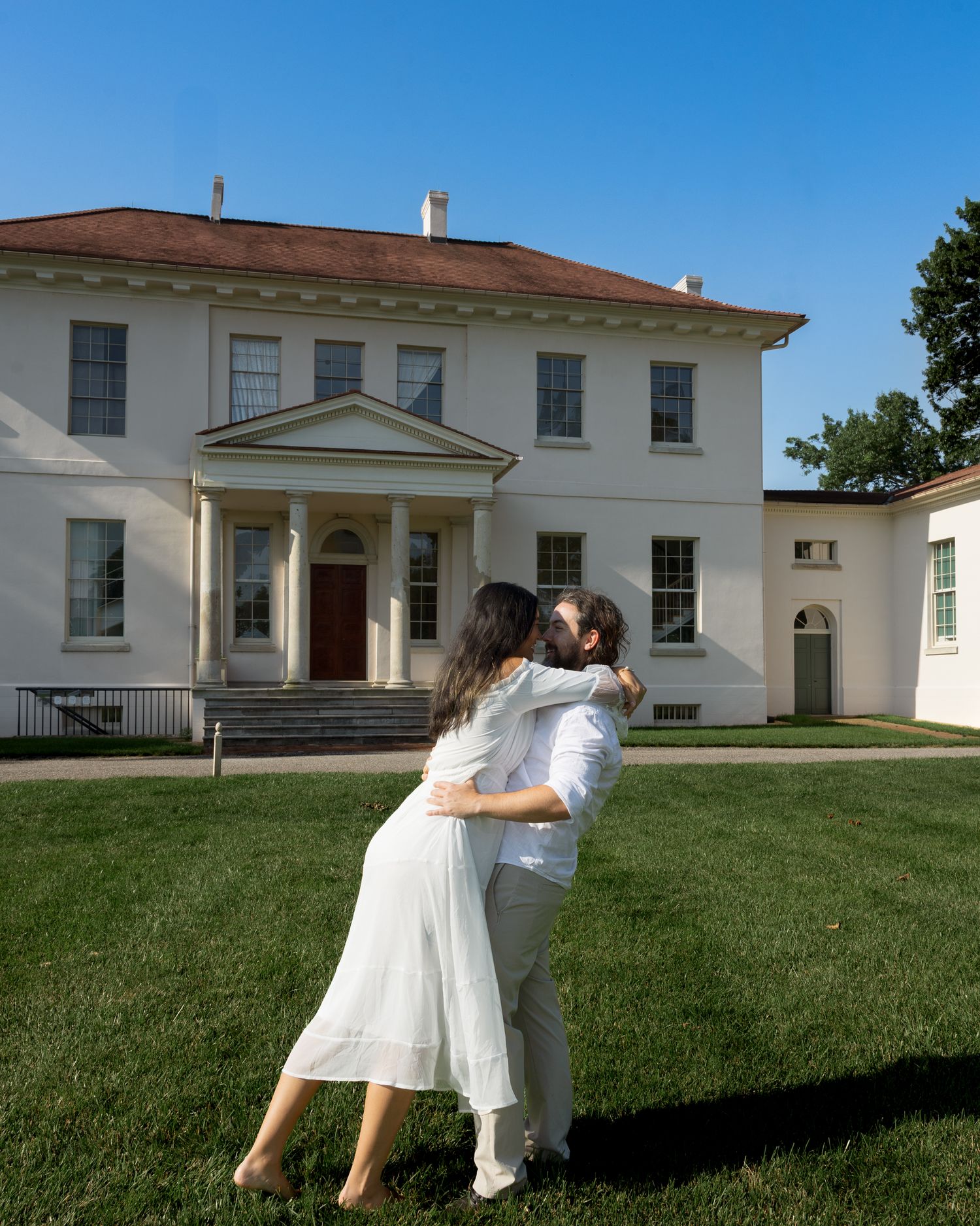 A sequence of images showing two people in white dresses dancing and twirling on a grassy lawn in front of a white building.