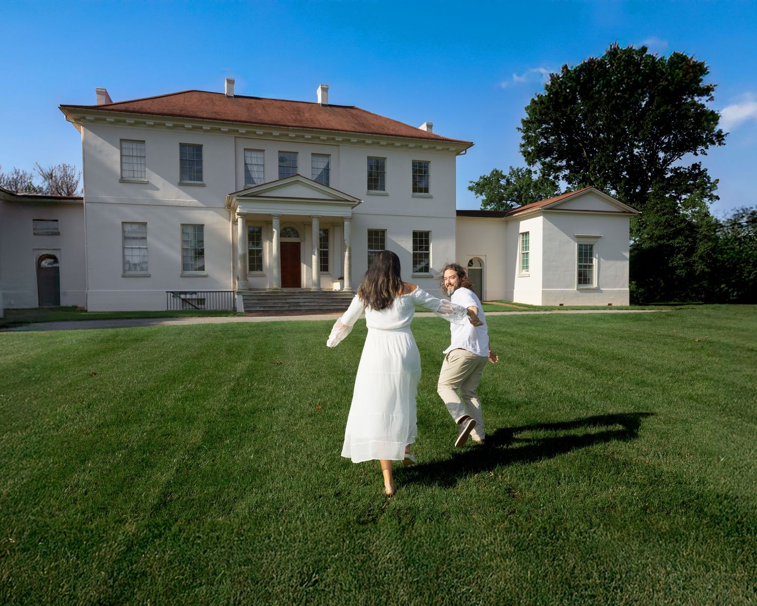 A sequence of panoramic shots showing people in white clothing rolling down a grassy hillside on a sunny day.