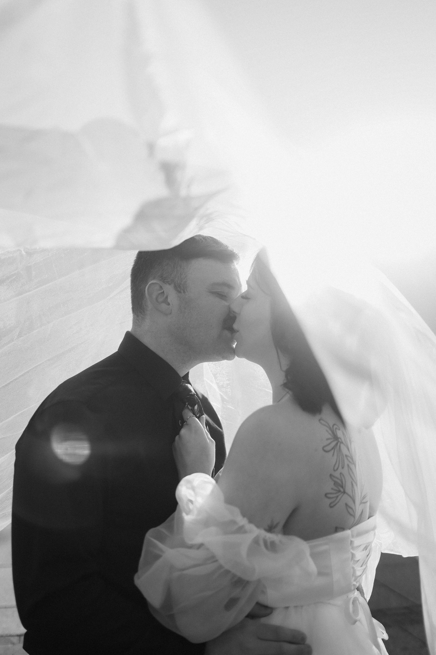 A romantic black and white wedding photo sequence showing a couple kissing under a flowing veil.