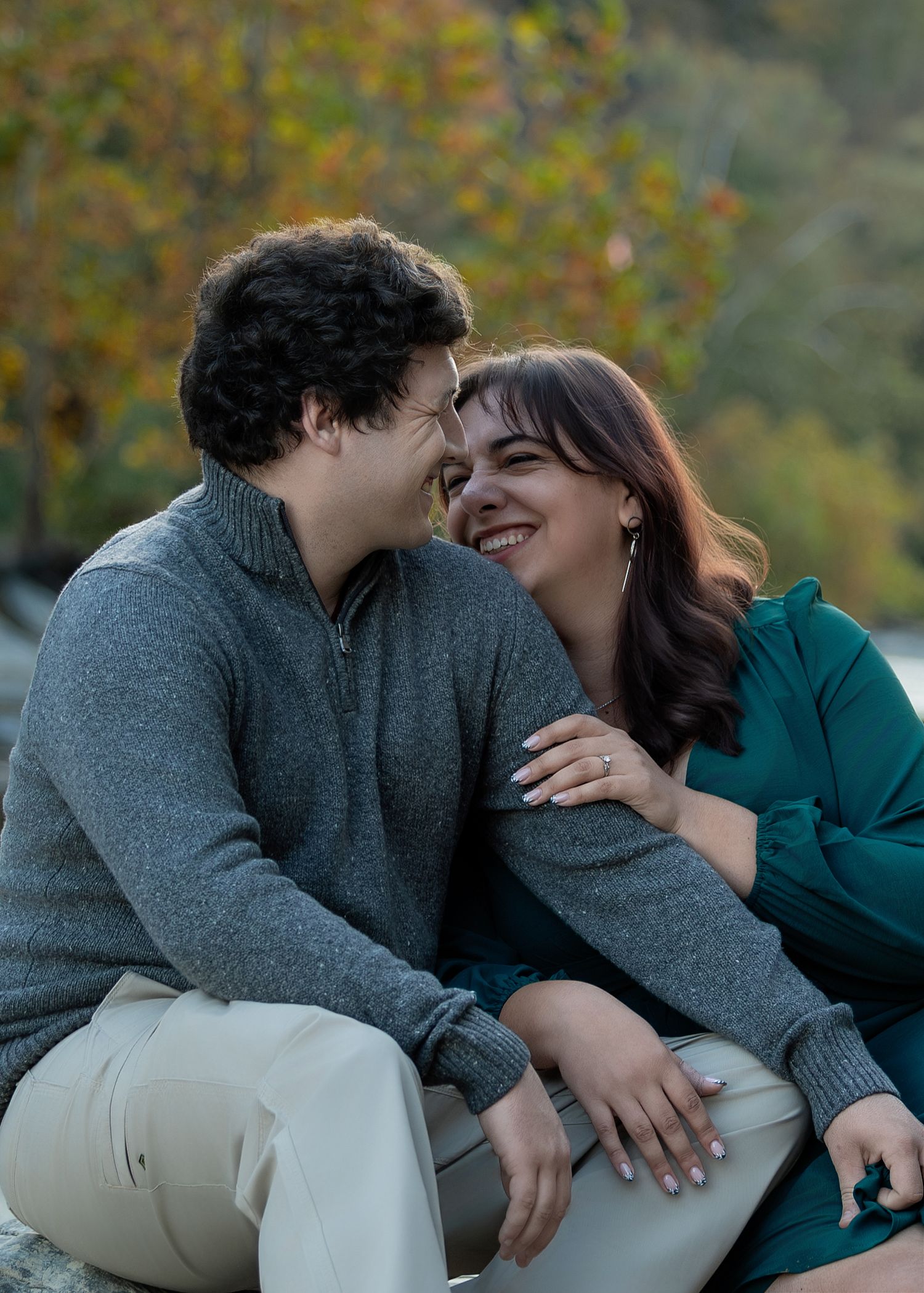 A couple sharing an intimate moment outdoors while wearing cozy sweaters against an autumn backdrop.