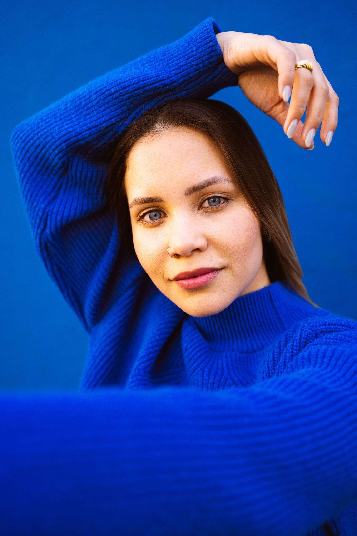 Fashion portrait series with bright blue sweater against vibrant blue background.