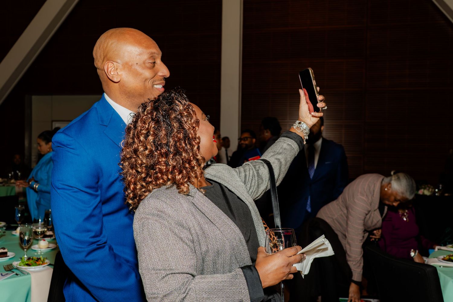 Guests using mobile phones during an evening social gathering.