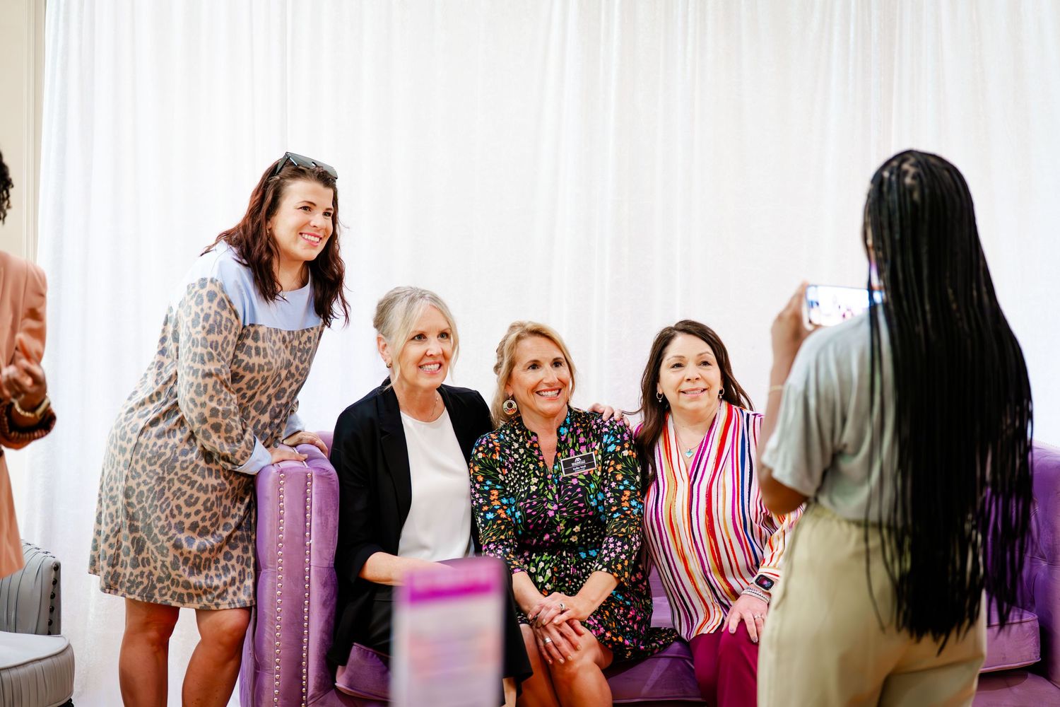 Workshop participants interacting in a bright conference room with white curtained walls.