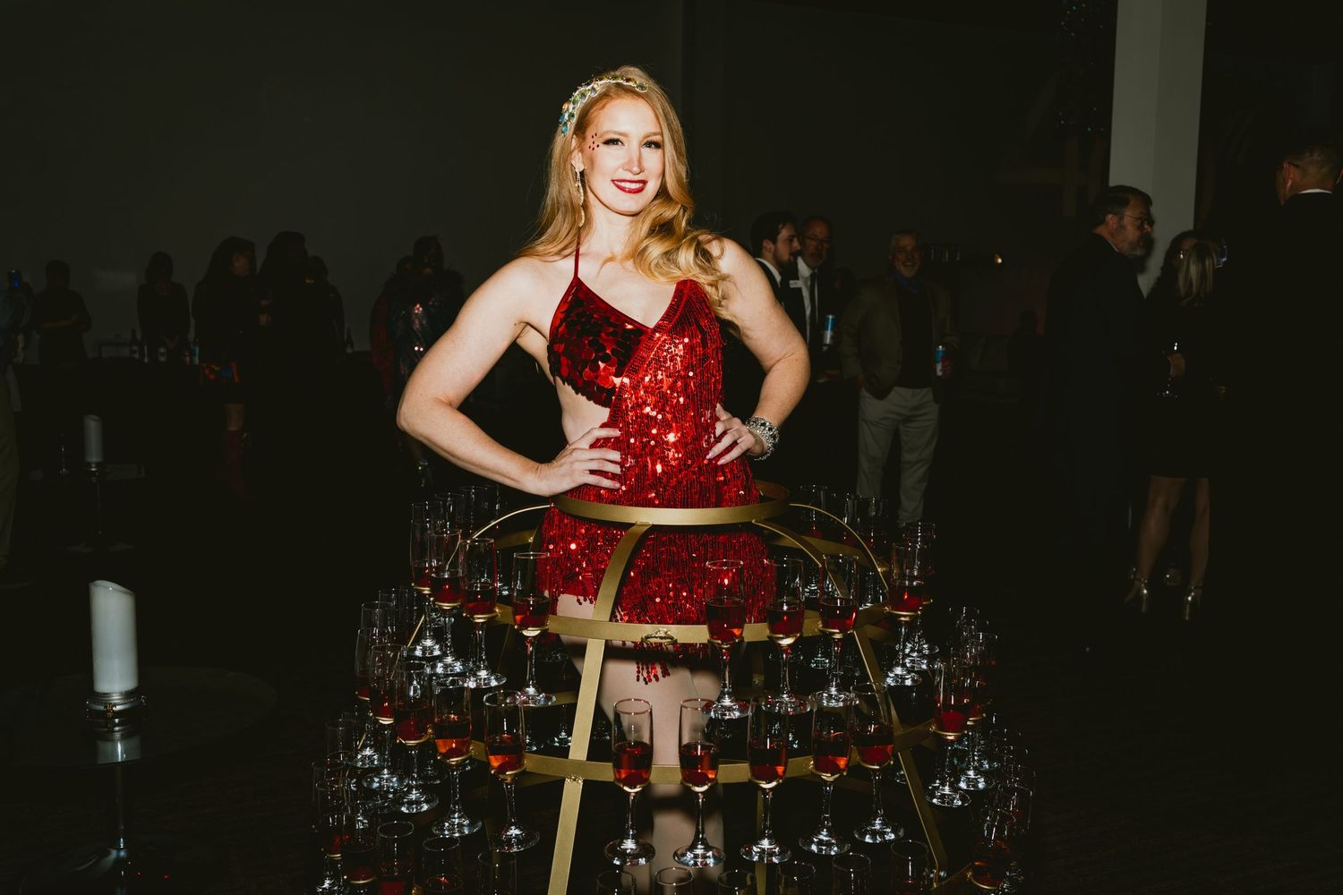 Red sparkly dress on stage with twinkling holiday lights in background.