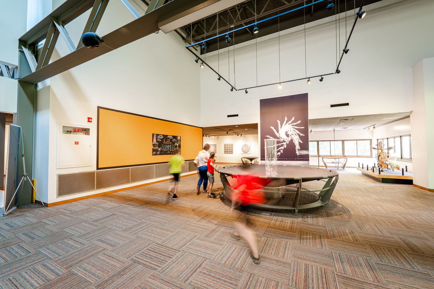 Empty modern gallery space with white walls and wooden floors shown in panoramic view.