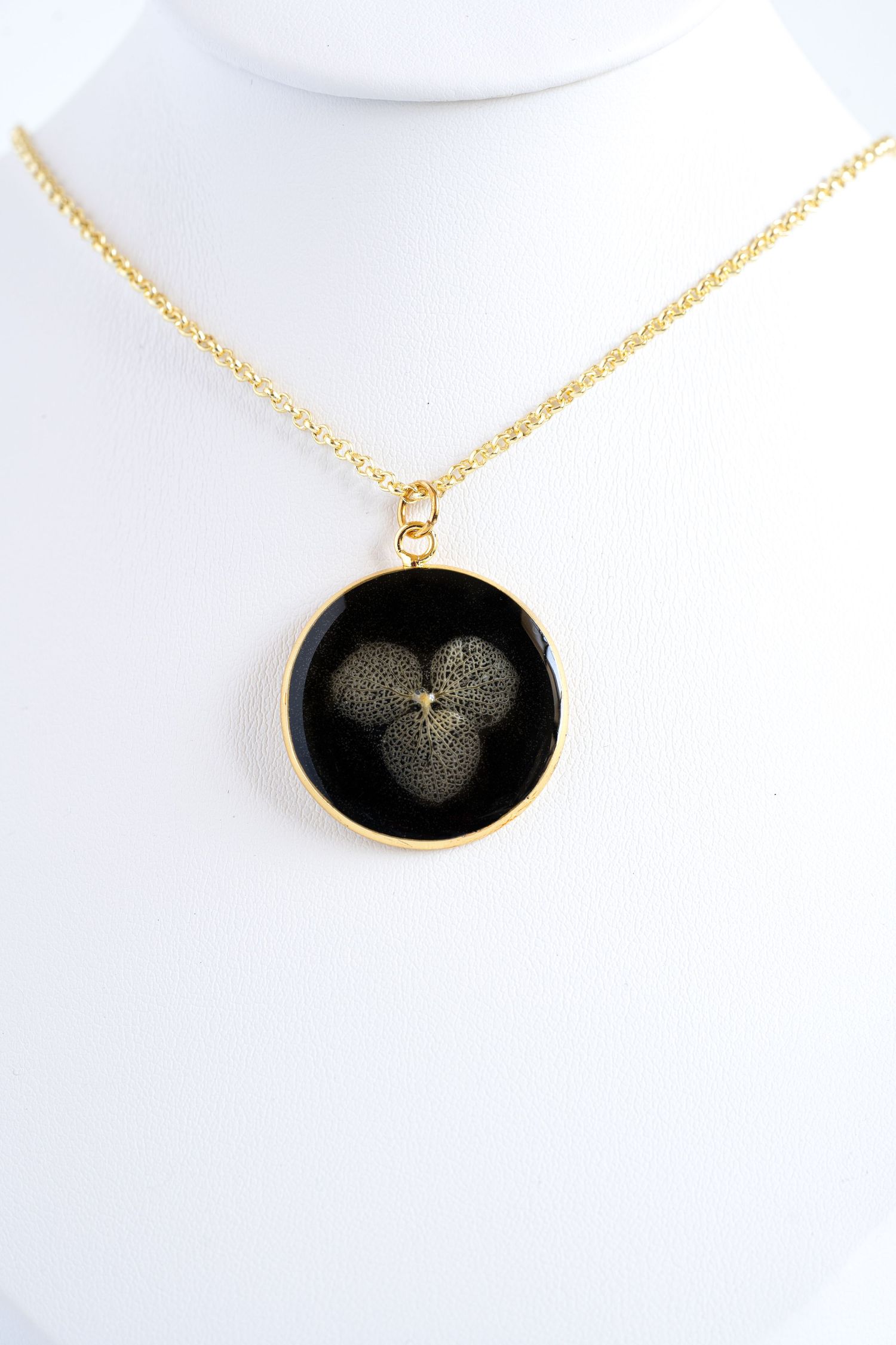 Black and gold pendant necklace displayed on white background.