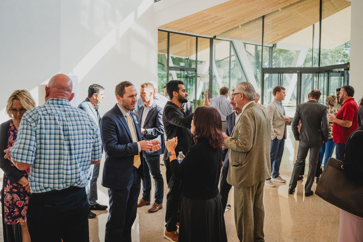 Networking event with attendees mingling in a modern glass-walled venue.