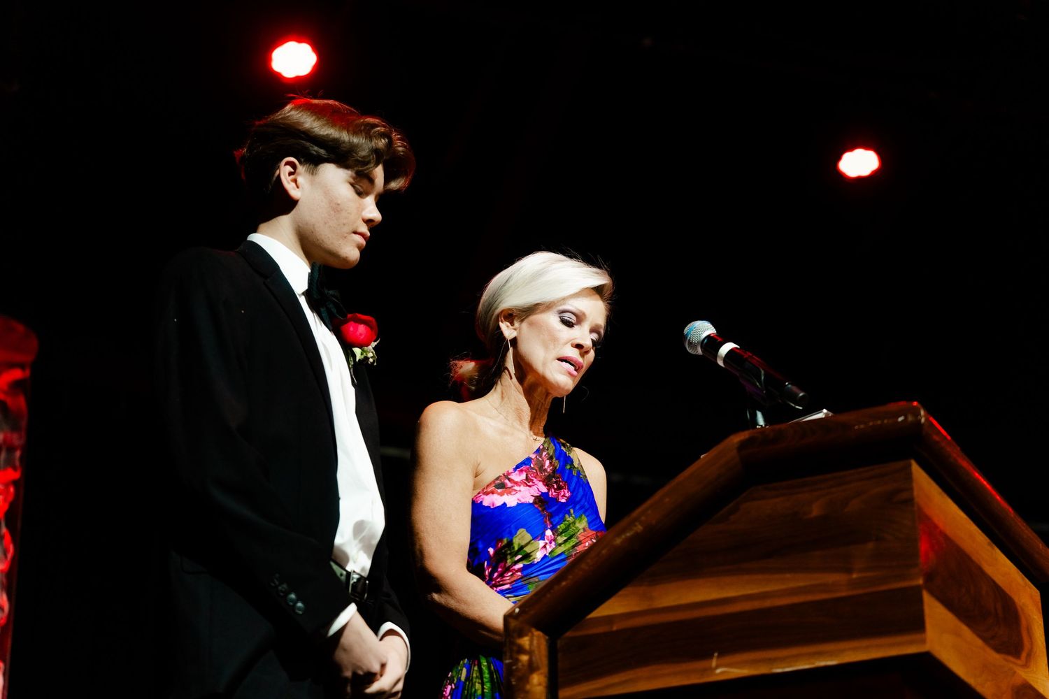 Stage performers at formal event with dramatic lighting and piano.